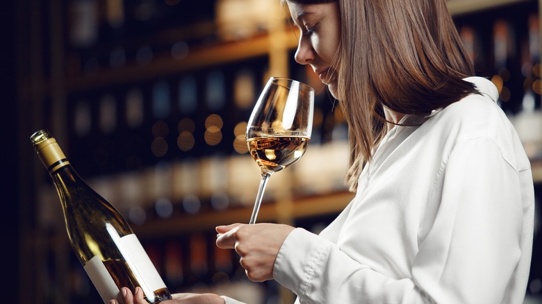 Person smelling wine, holding bottle