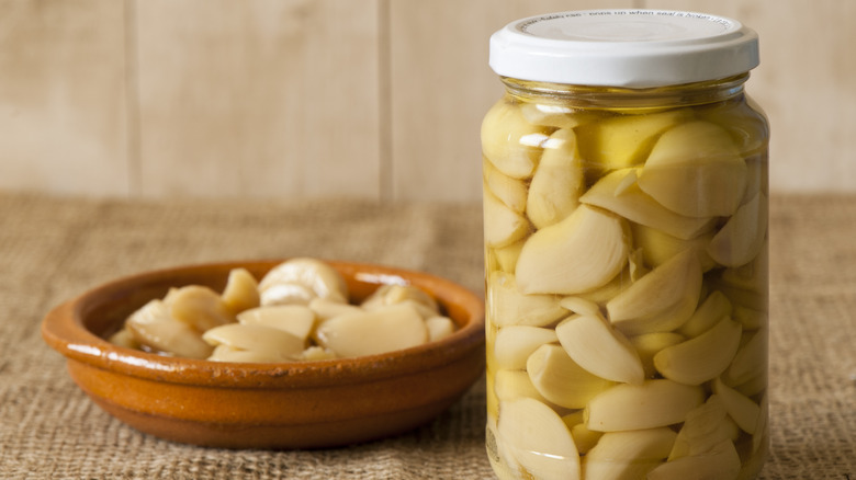 jar of garlic confit with bowl of cloves