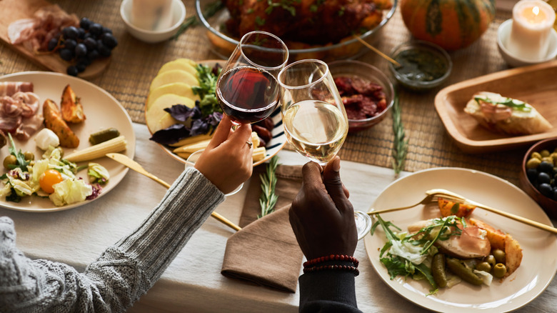 toasting wine glasses over dinner table