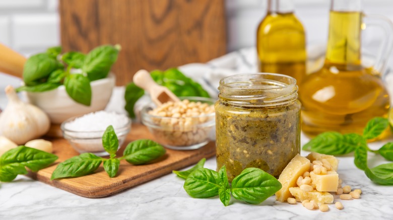 pesto in a jar surrounded by pesto ingredients