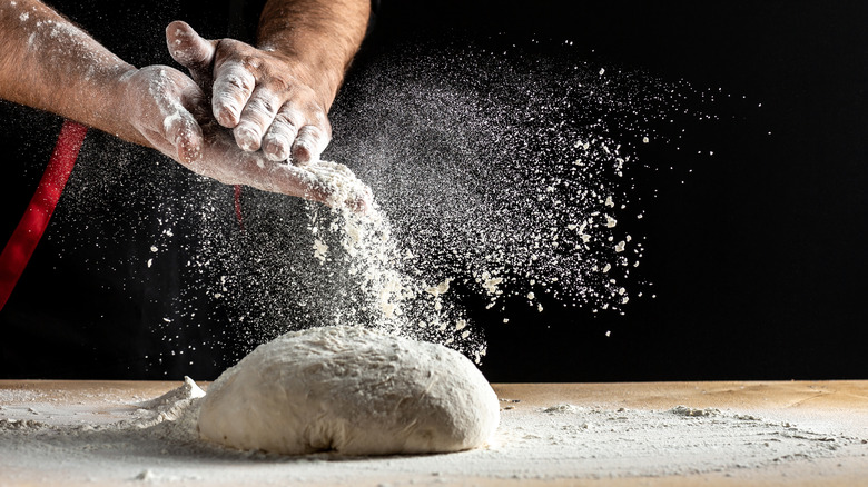 Someone dusting dough with flour