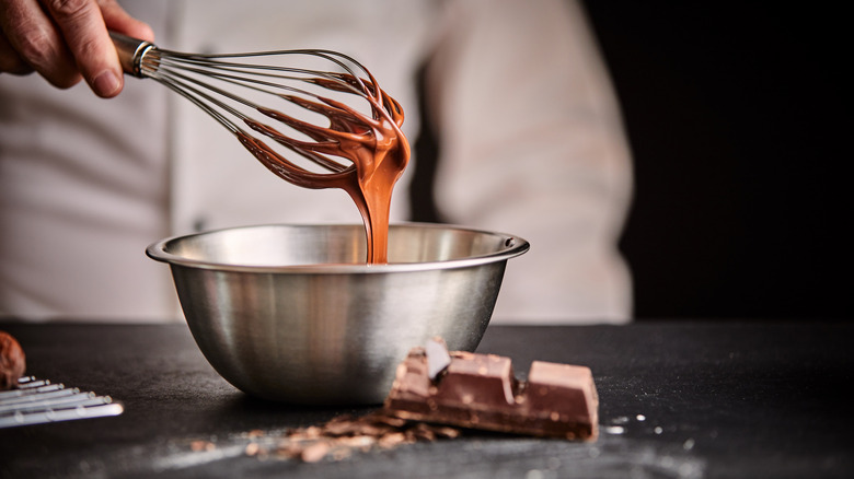 whisking chocolate in a bowl with a hand whisk