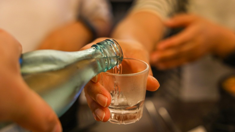 hand pouring raised soju glass