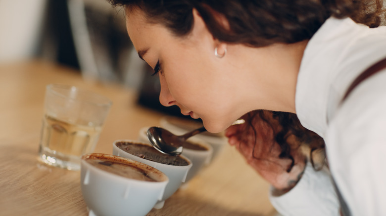 woman smelling coffee at coffee cupping