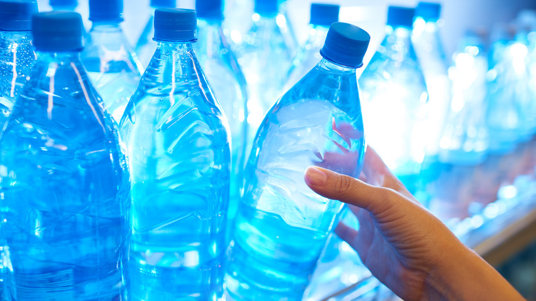 A hand taking a water bottle from a shelf