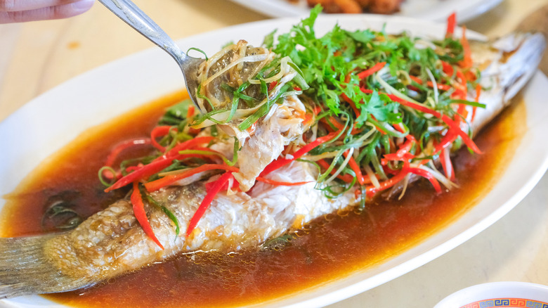 Whole steamed sea bass covered in seasonings