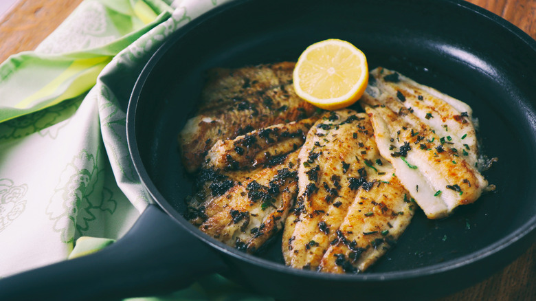 Flounder fillets in pan with halved lemon