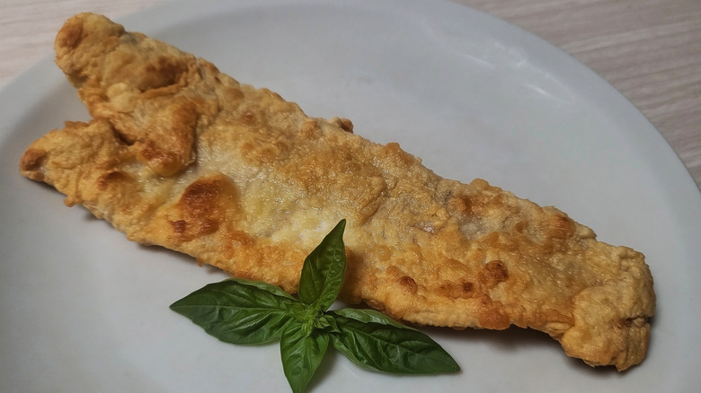 Fried hake fillet with basil garnish