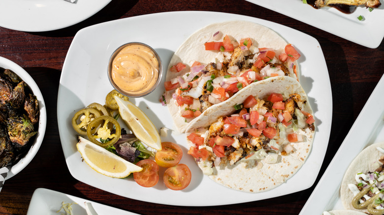 Fish tacos made with halibut, with pico de gallo on top and salad to side