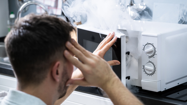 Man opening smoke-filled microwave
