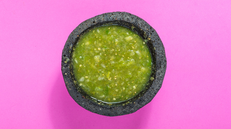 Salsa verde in a molcajete against purple background