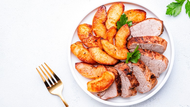 Pork tenderloin slices with apples on plate