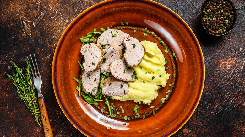 Pork tenderloin slices with mashed potatoes on plate