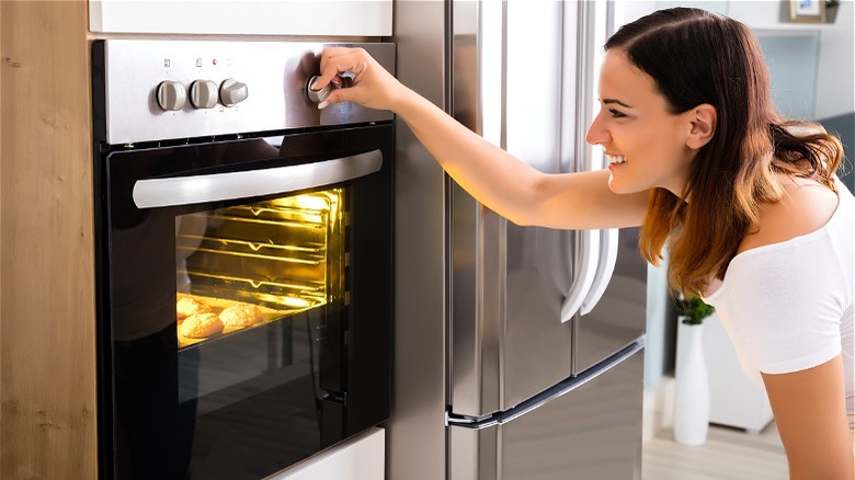 woman turning oven dial