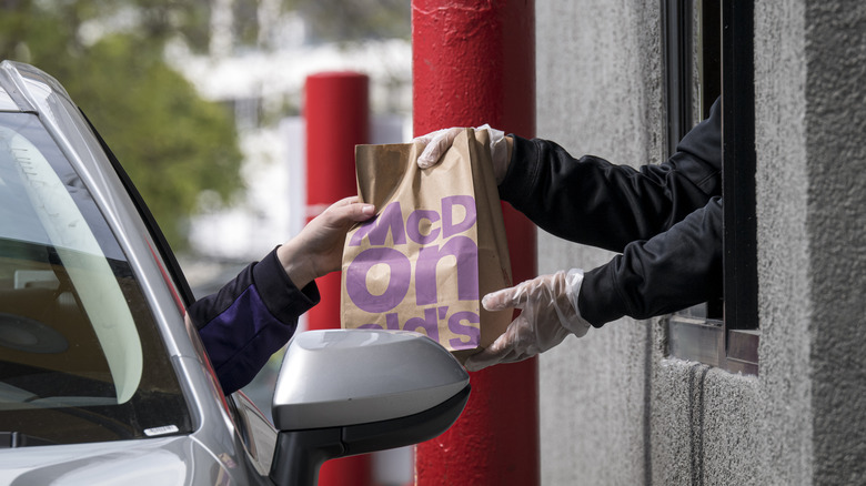 McDonald's worker handing bag to car in drive-thru