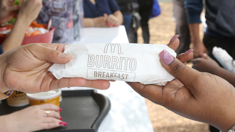 Customers holding wrapped breakfast burrito