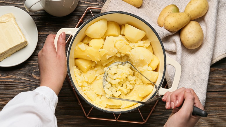 hands mashing potatoes in a pot