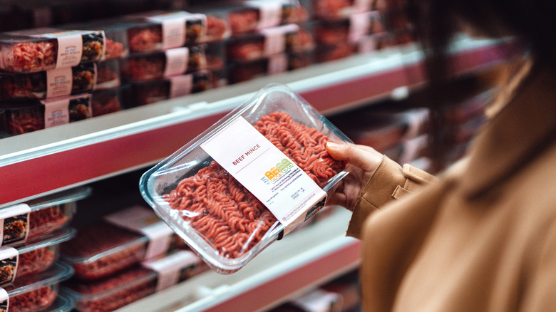 woman looking at package of ground beef