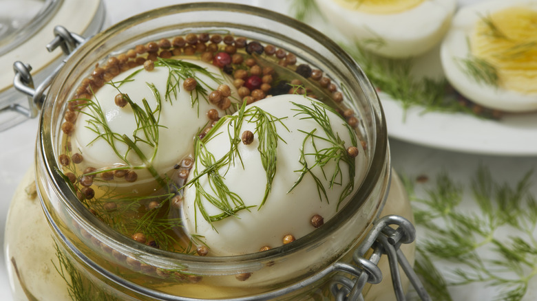 Pickled eggs in a jar with herbs and spices