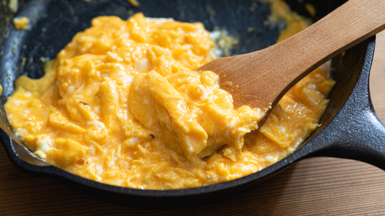 scooping scrambled eggs with wooden spatula