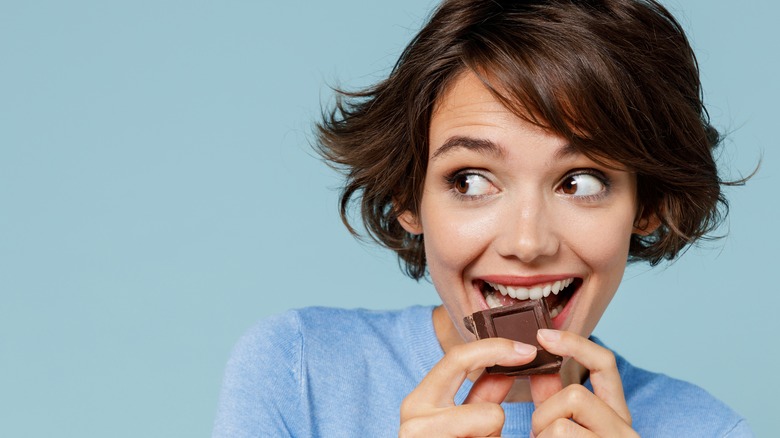 Person eating square of dark chocolate