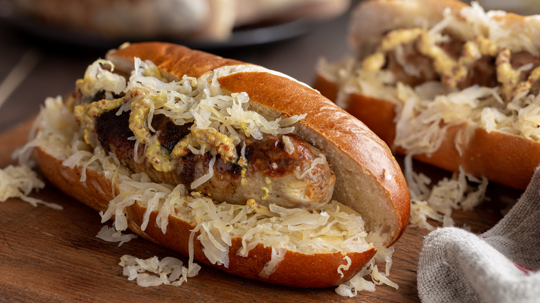 A bratwurst in a pretzel bun covered in onions and mustard