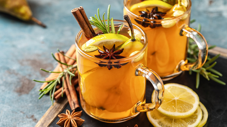 Spiced drink with lemon rosemary in glass mugs