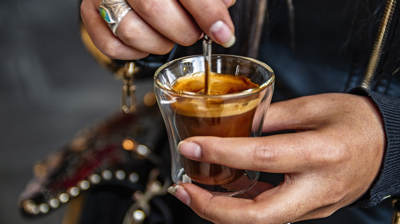 person stirring a creamy espresso