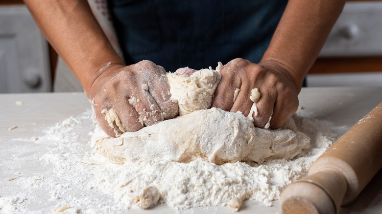 hands kneading pizza dough