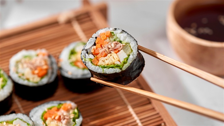 Chopsticks holding sushi roll