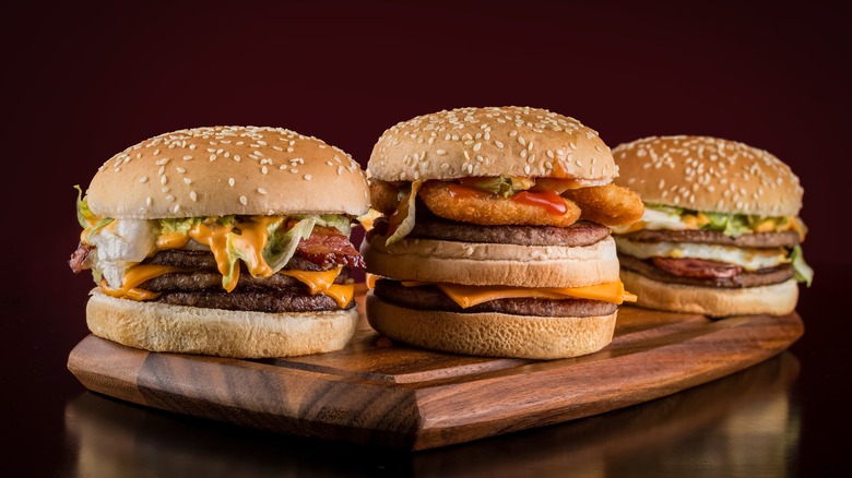 Three burgers on wooden board