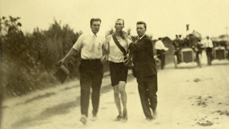 Thomas Hicks carried across finish line