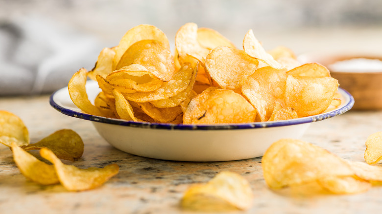 Bowl of potato chips surrounded by more chips