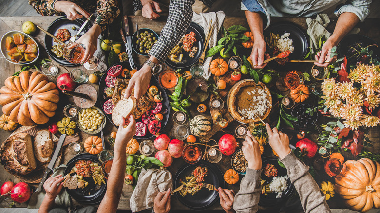 Four friends around table laid with Thanksgiving fare