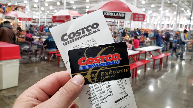 Hand holding Costco receipt and membership card