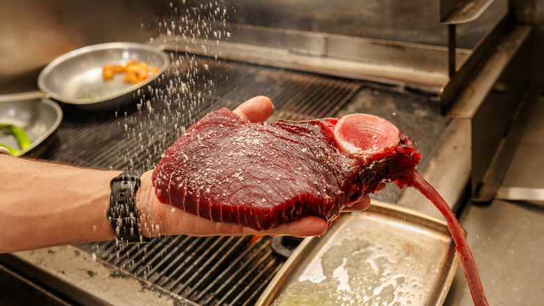 chef salting dry-aged tuna steak