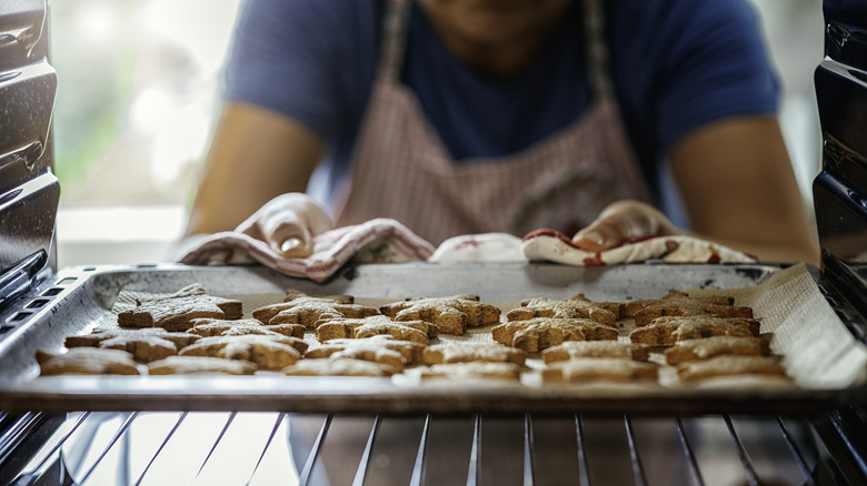 A person grabbing cookies out of the oven