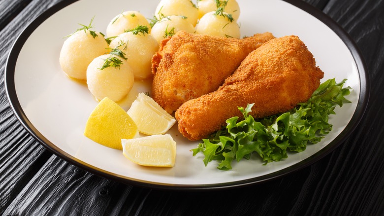 Fried chicken on plate with potatoes and lemon