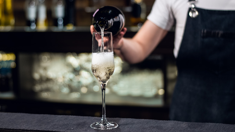 Bartender pouring sparkling wine into glass