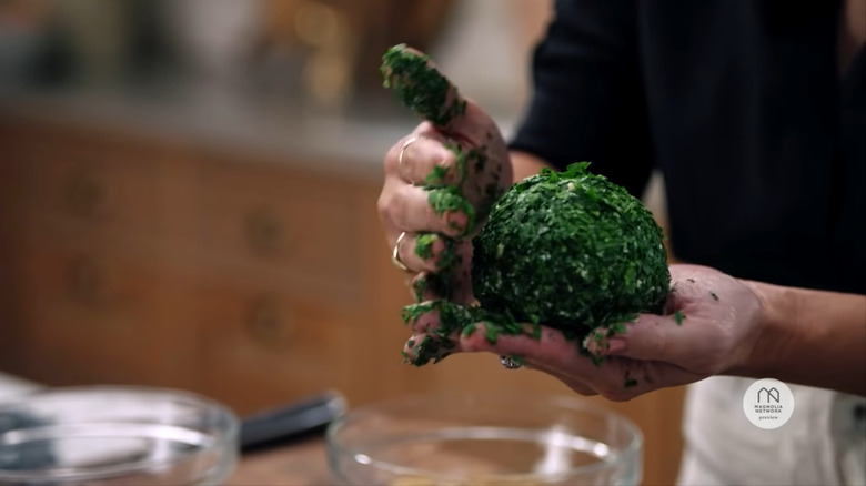 Joanna Gaines coating the cheese ball in parsley with her hands