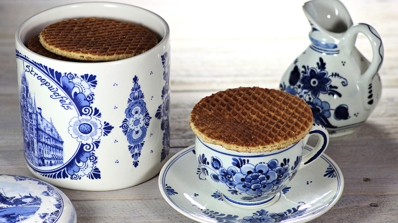 Stroopwafels in white ceramic jar and stroopwafel on top of coffee cup