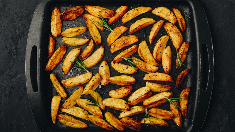 Potato wedges with rosemary on tray