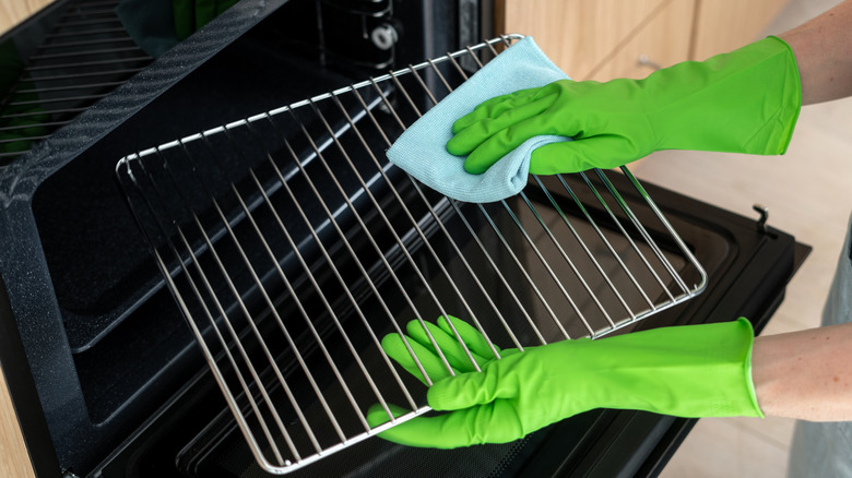 gloved hands wiping and replacing oven rack