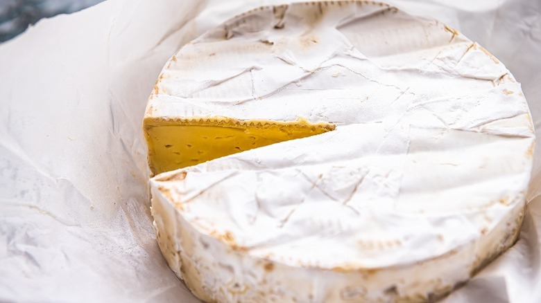 wheel of brie with missing wedge on cheese paper