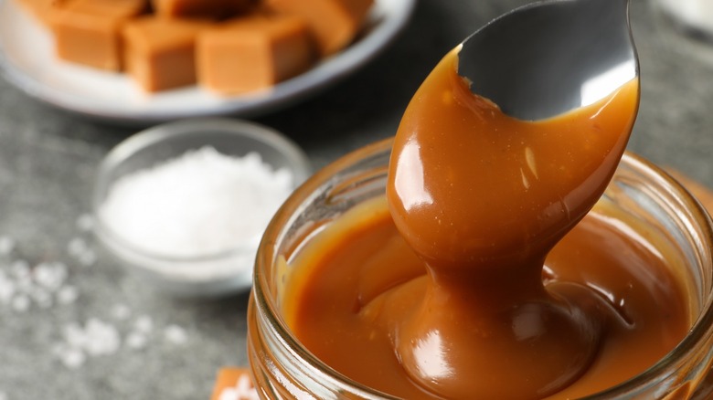 butterscotch syrup drizzling off a spoon into a mason jar