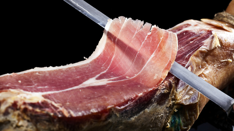 Knife slicing prosciutto