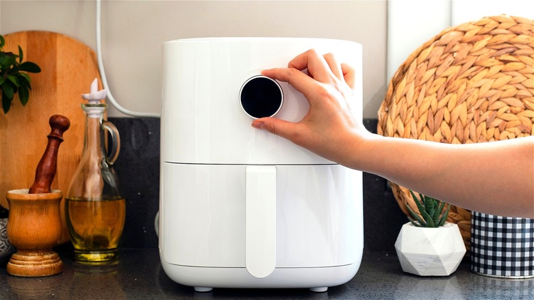 Hand turning dial on air fryer 