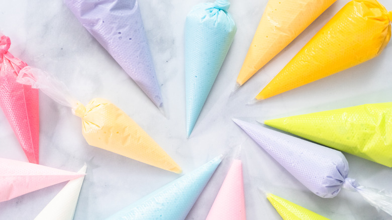 Person frosting cupcakes with a piping bag