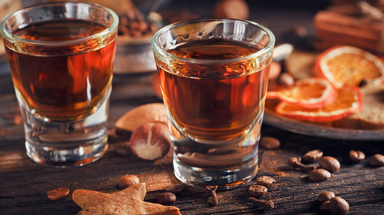 Two glasses of bourbon next to coffee beans and dried orange slices