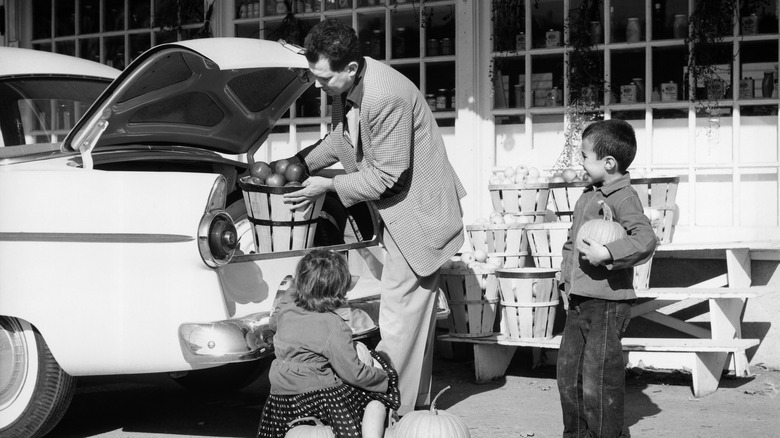 1950s family loading car with produce